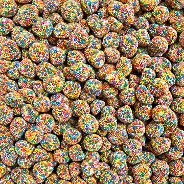 A close-up, top-down view of many small round candies coated in colorful sprinkles, filling the entire frame.